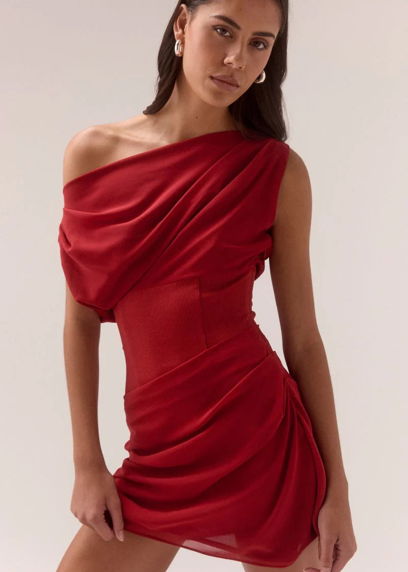 Woman wearing a red one-shoulder dress against a plain background