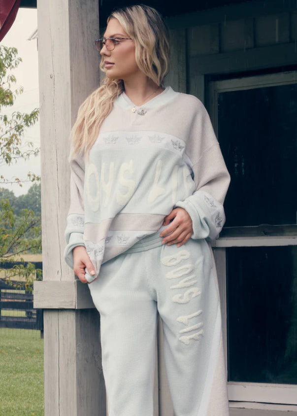 Woman wearing a light-colored outfit standing outdoors near a building.