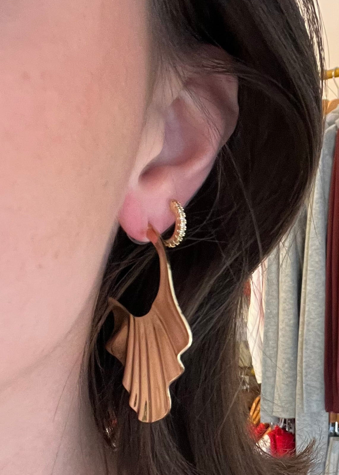 Close-up of a person wearing gold earrings with a store interior in the background