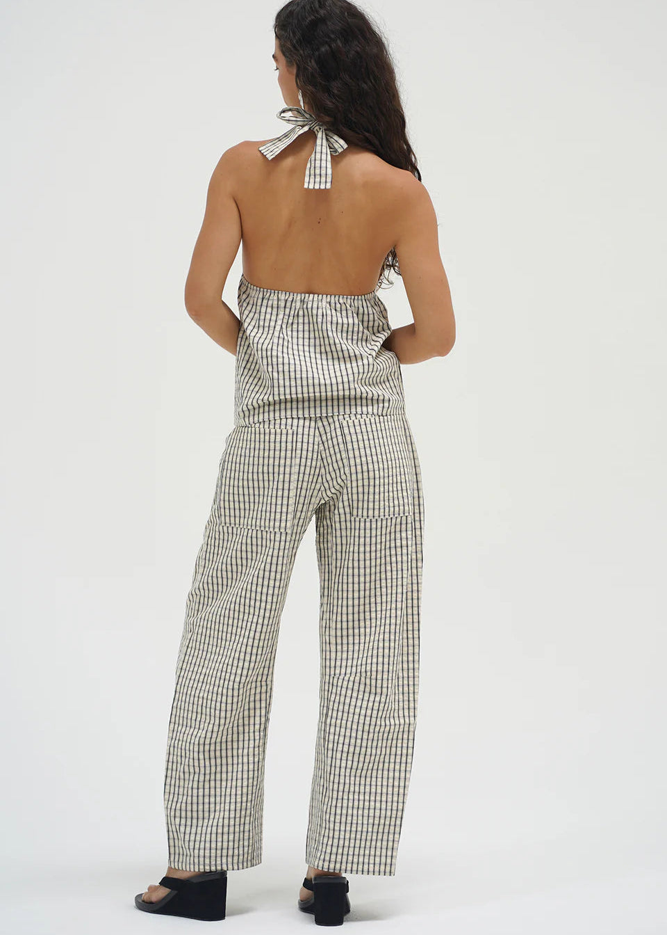 Woman wearing a checkered top and pants on a white background