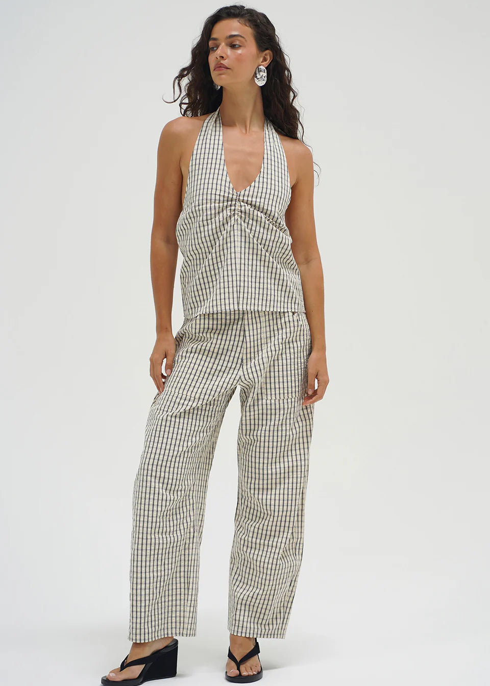 Woman wearing a checkered pants on a white background. lna clothing.
