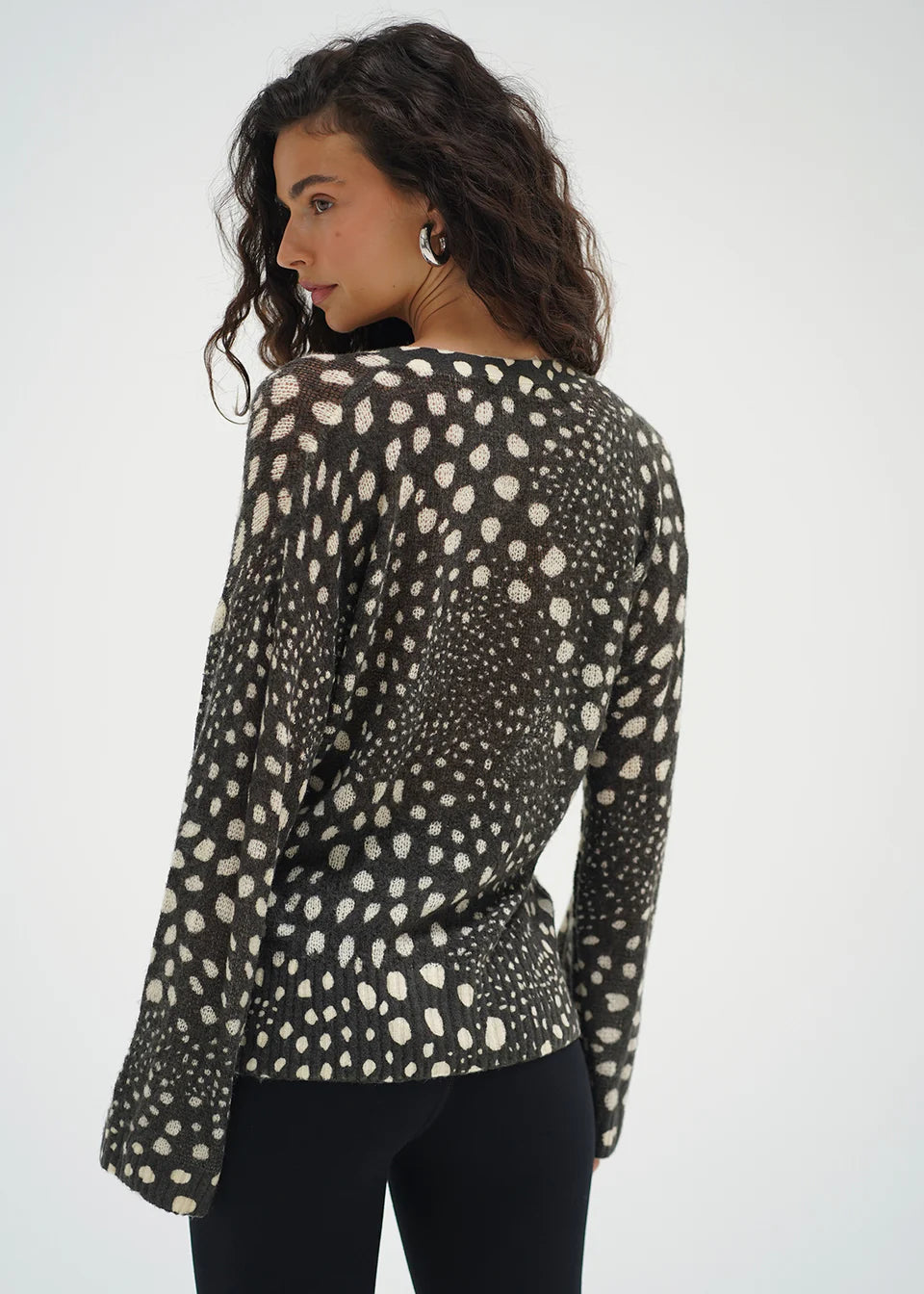 Woman wearing a long-sleeve top with a black and white pattern on a white background