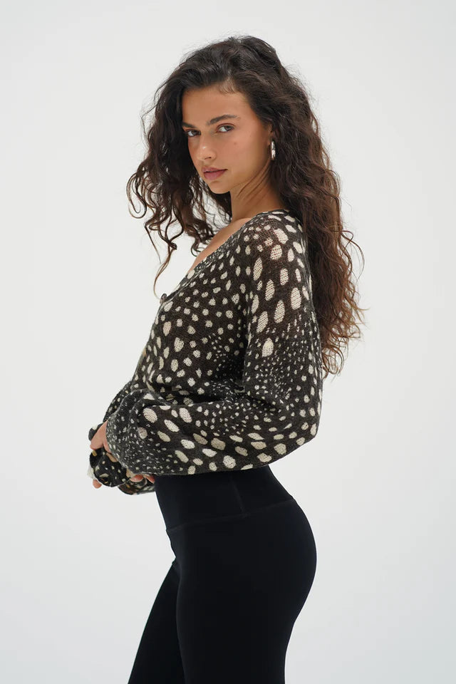 Woman wearing a black and white patterned top with long sleeves on a white background