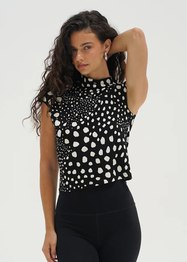 Woman wearing a black sleeveless top with white pattern on a plain background. LNA Clothing.
