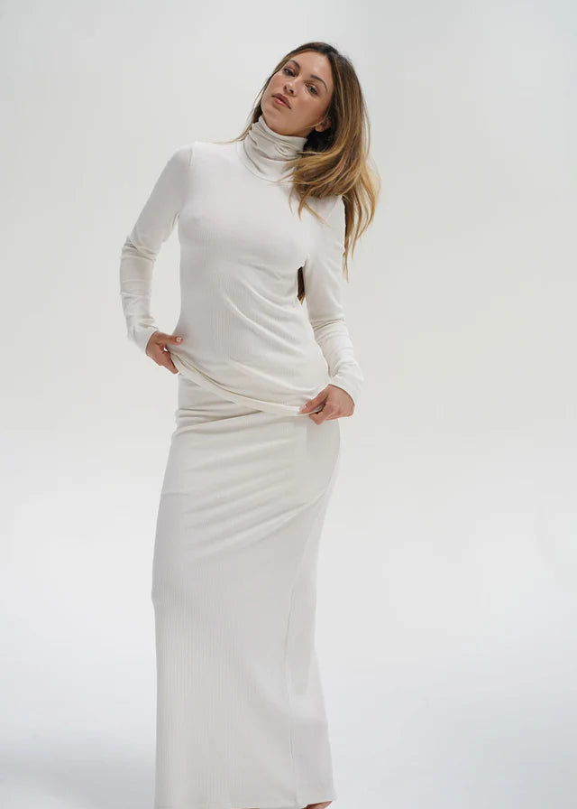 Woman wearing a long white dress against a white background