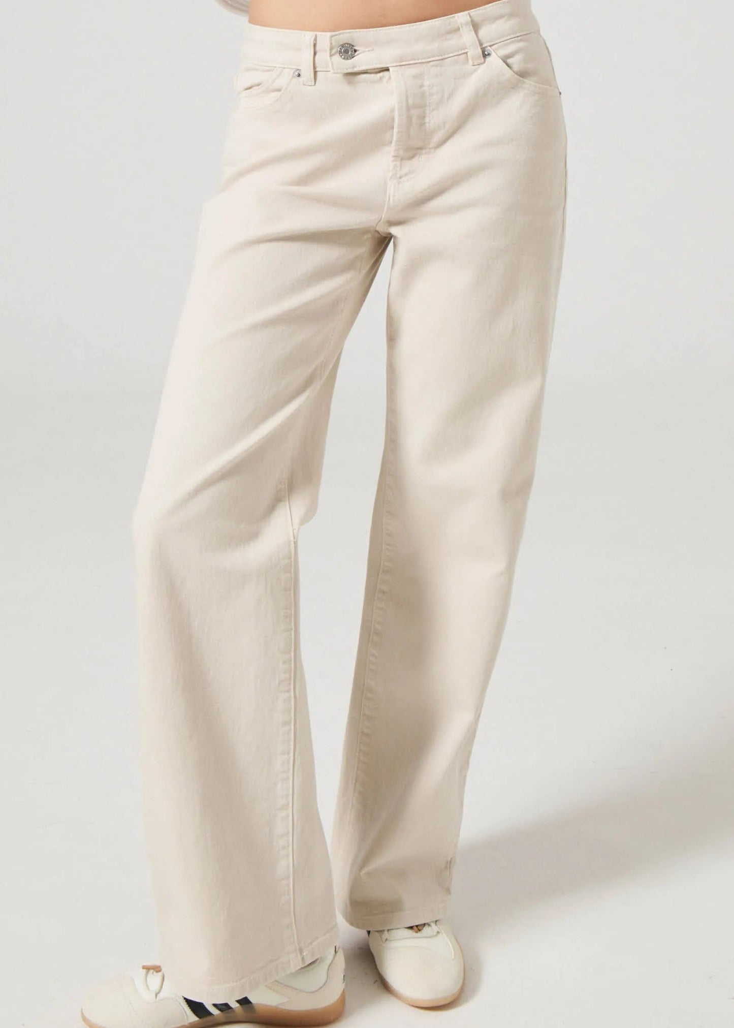 Beige pants worn by a person on a plain background. Rollas heidi low rise jeans. fayetteville arkansas.