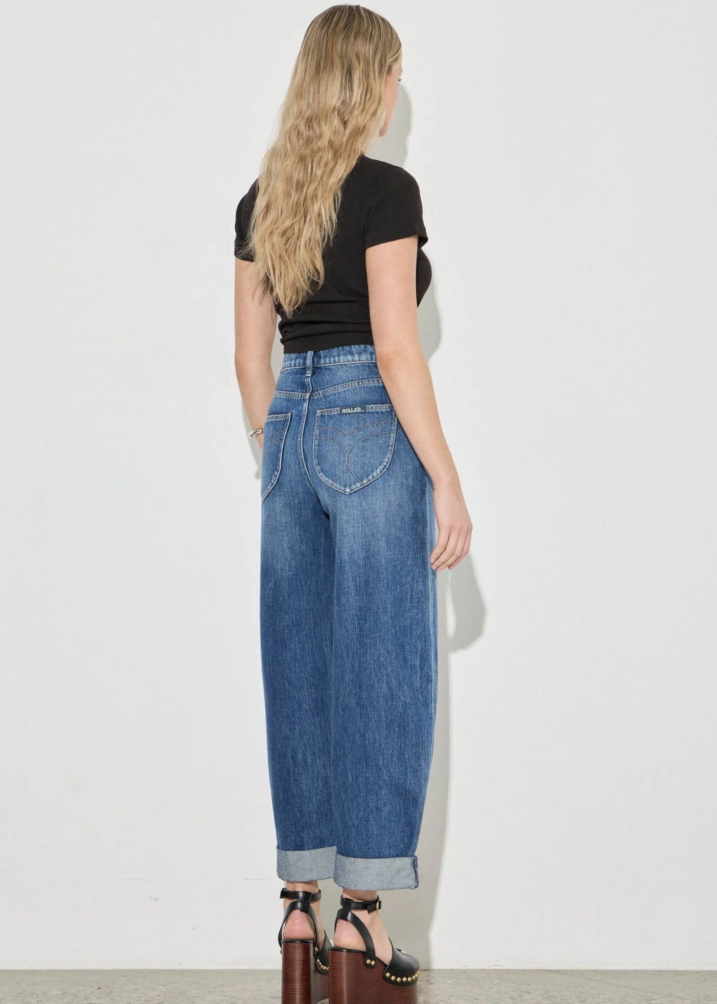 Woman wearing blue jeans and a black top against a white background