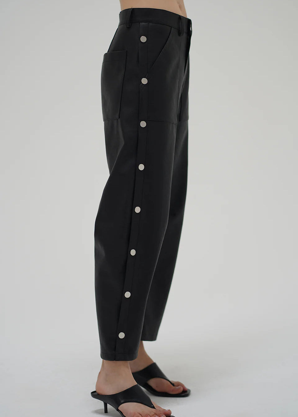 Black pants with white buttons on a gray background