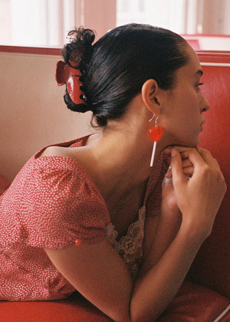 Woman sitting on a red couch wearing a pink top with a lace detail.