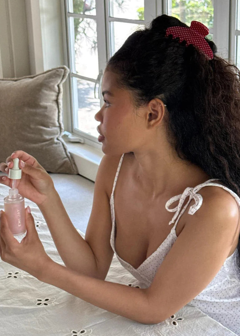 Young girl holding a pink bottle in a bedroom setting