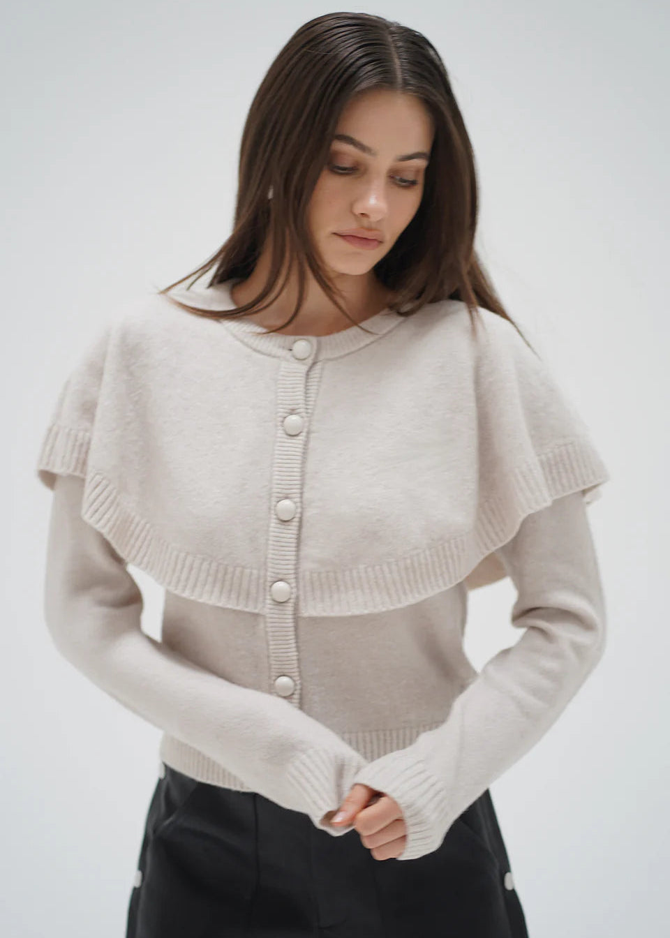 Woman wearing a beige knitted cardigan against a white background