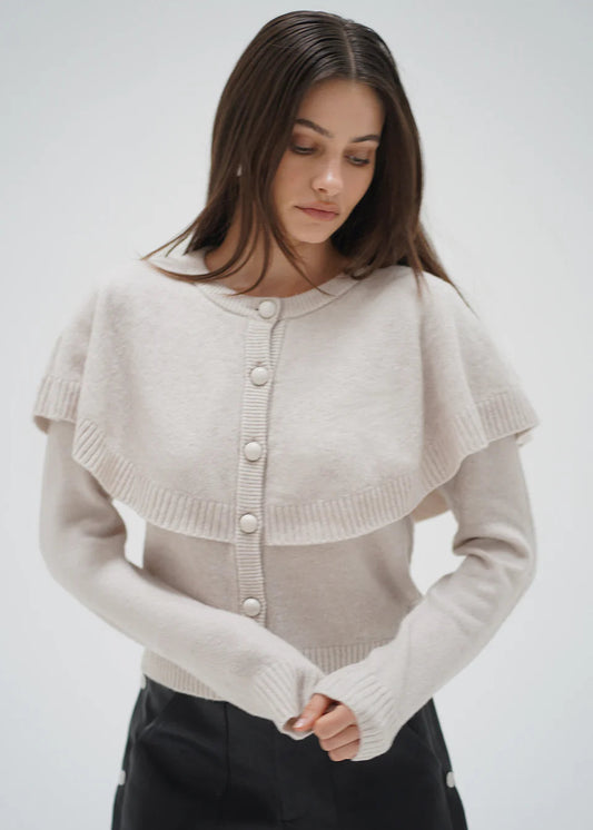 Woman wearing a beige knitted cardigan against a white background