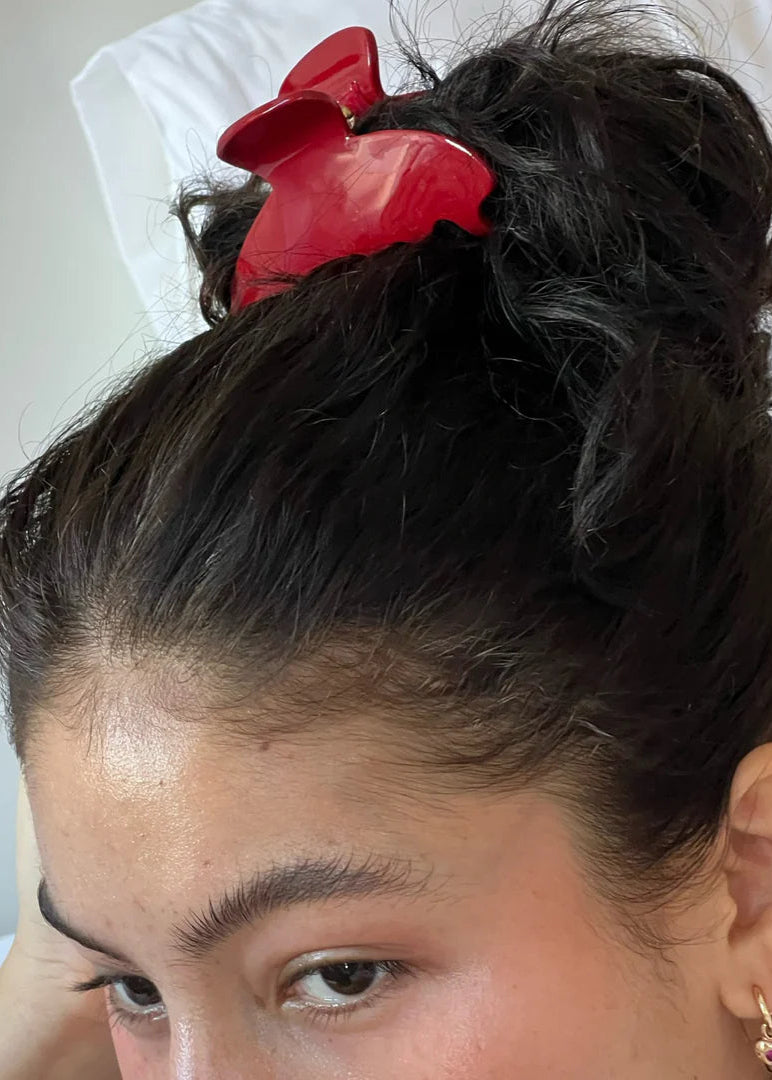 Person with a high ponytail and red hair tie on a light background