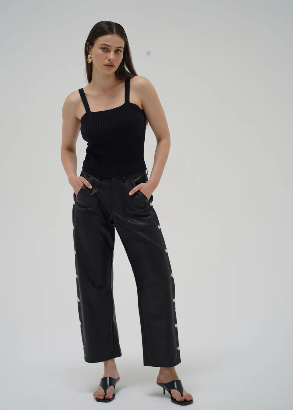 Woman wearing a black sleeveless top and black pants on a white background