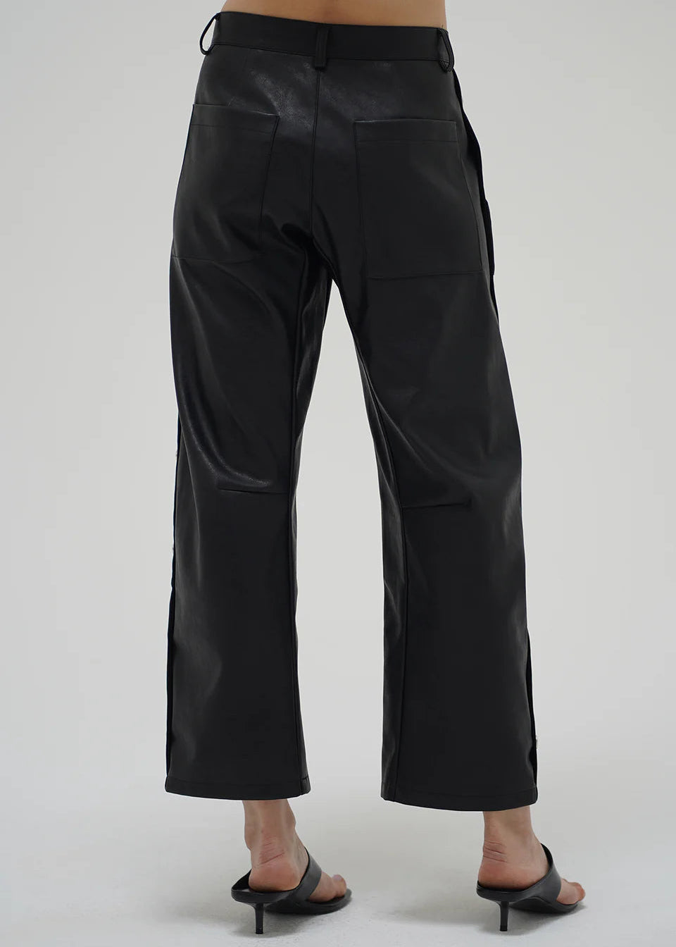 Black leather pants worn by a person on a white background