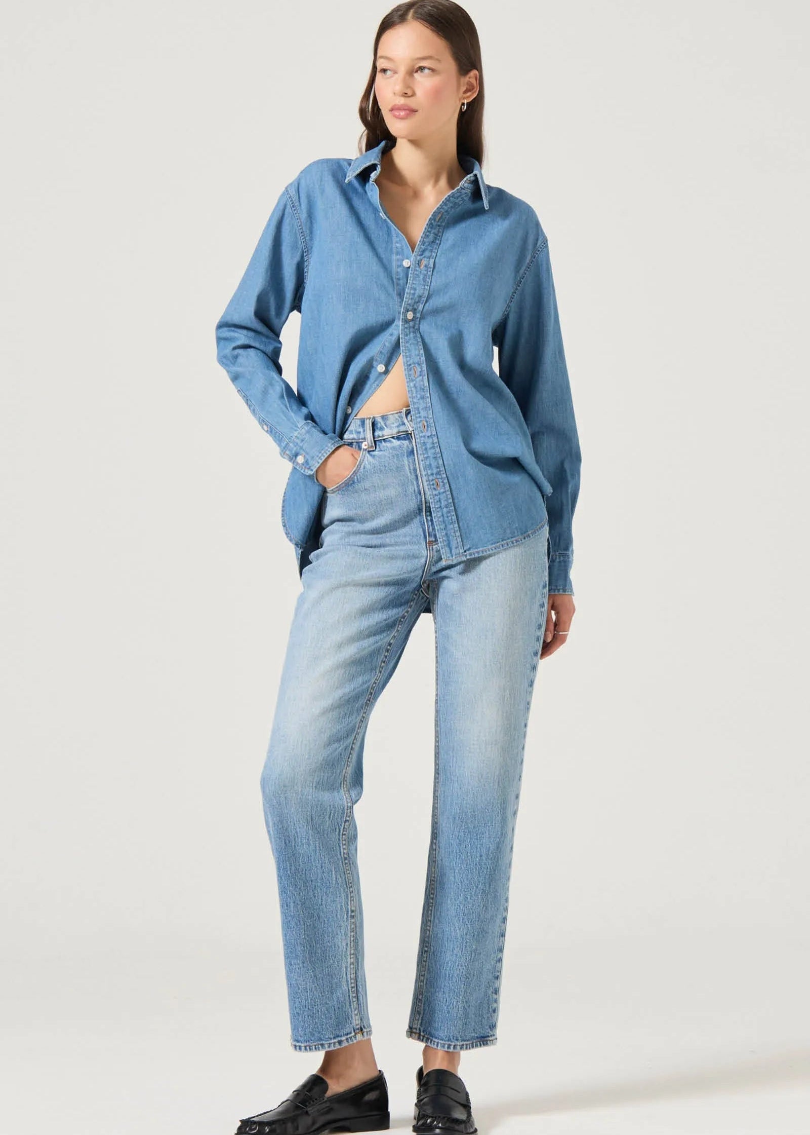 Woman wearing a blue denim shirt and jeans on a white background