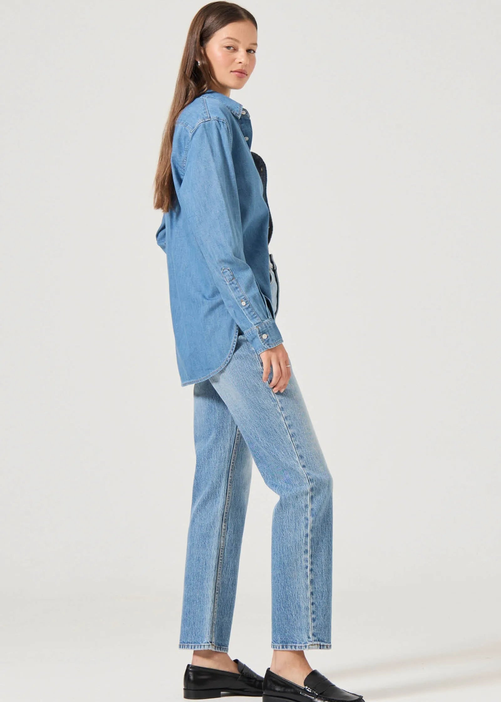 Woman wearing a blue denim shirt and jeans on a white background