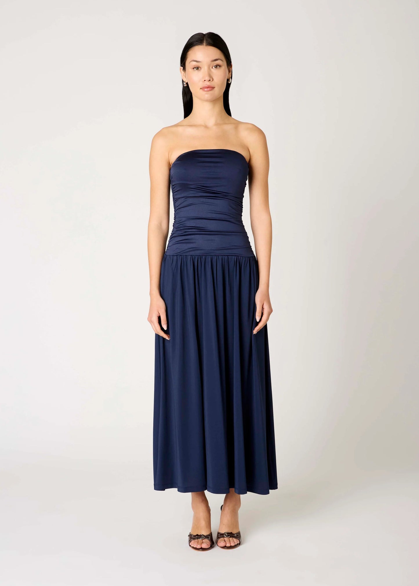 Woman wearing a strapless navy blue dress on a white background