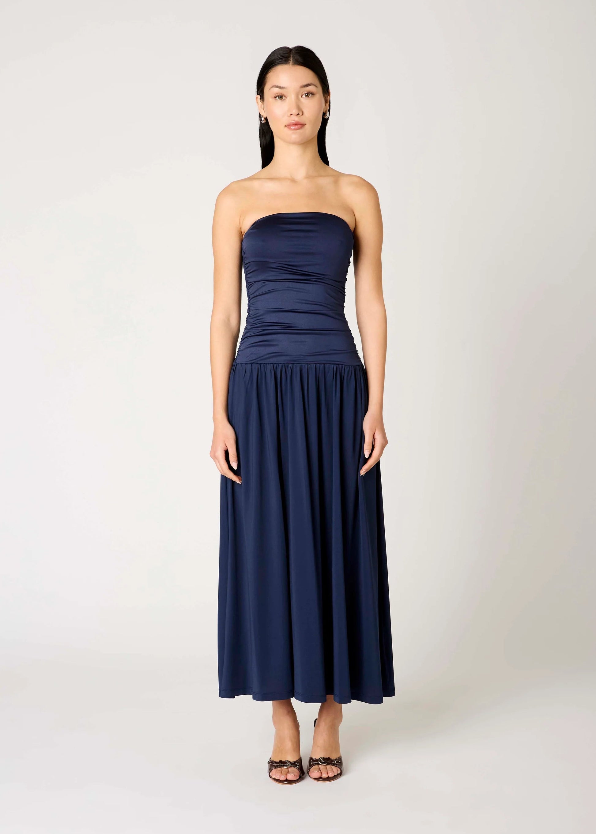 Woman wearing a strapless navy blue dress on a white background