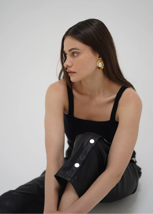 Woman wearing a black dress with gold buttons against a white background