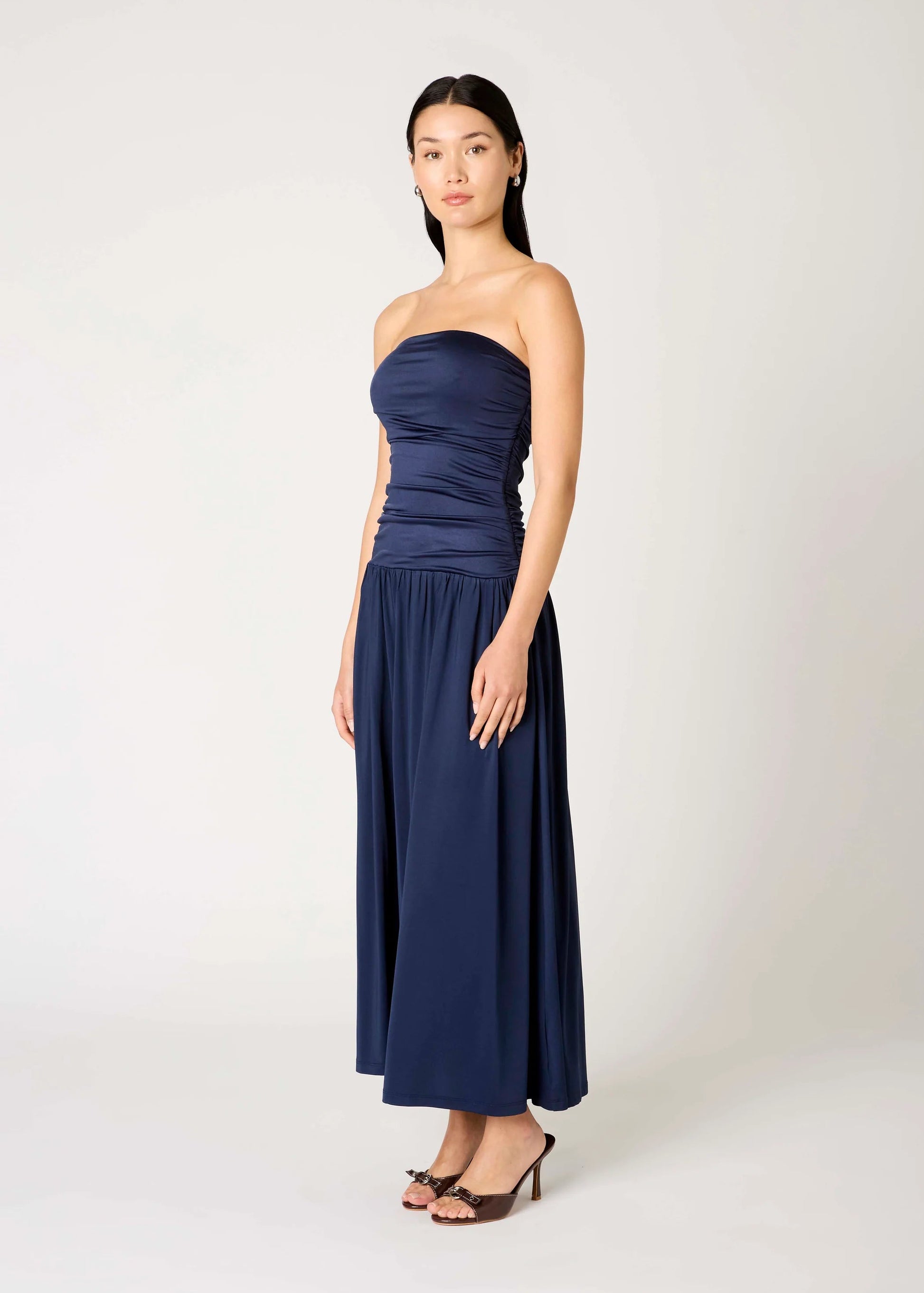 Woman wearing a strapless navy blue gown on a white background