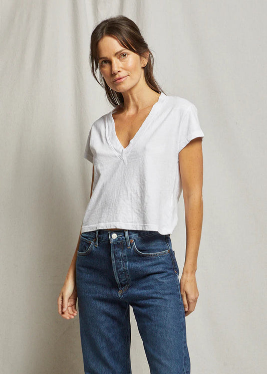 Woman wearing a white t-shirt and blue jeans against a plain background