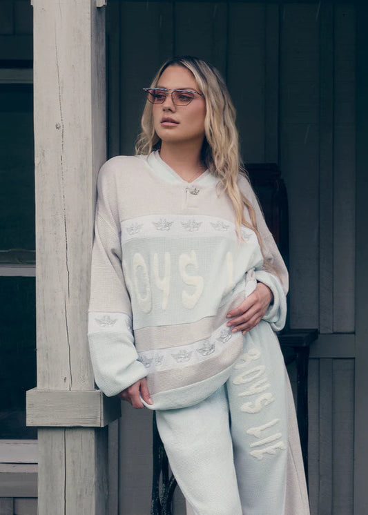 Woman wearing a light-colored outfit with text, standing outdoors.