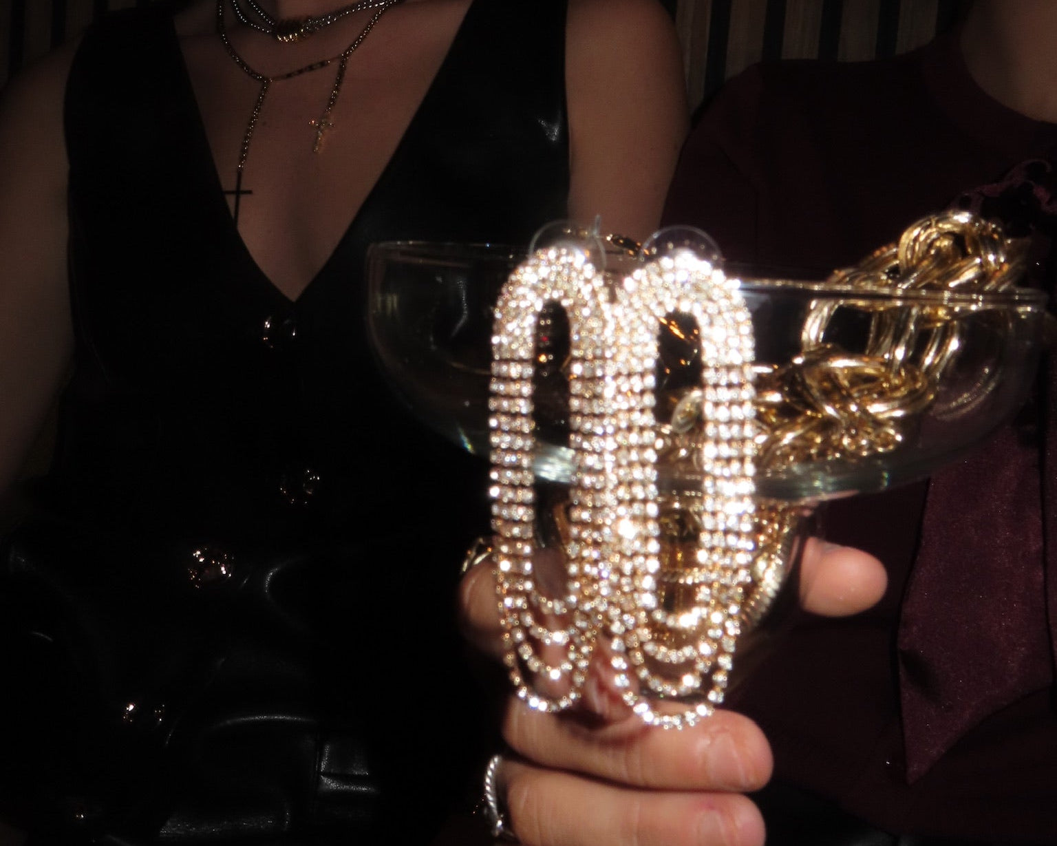 Two women holding a crystal-studded '00' glass with a festive background.