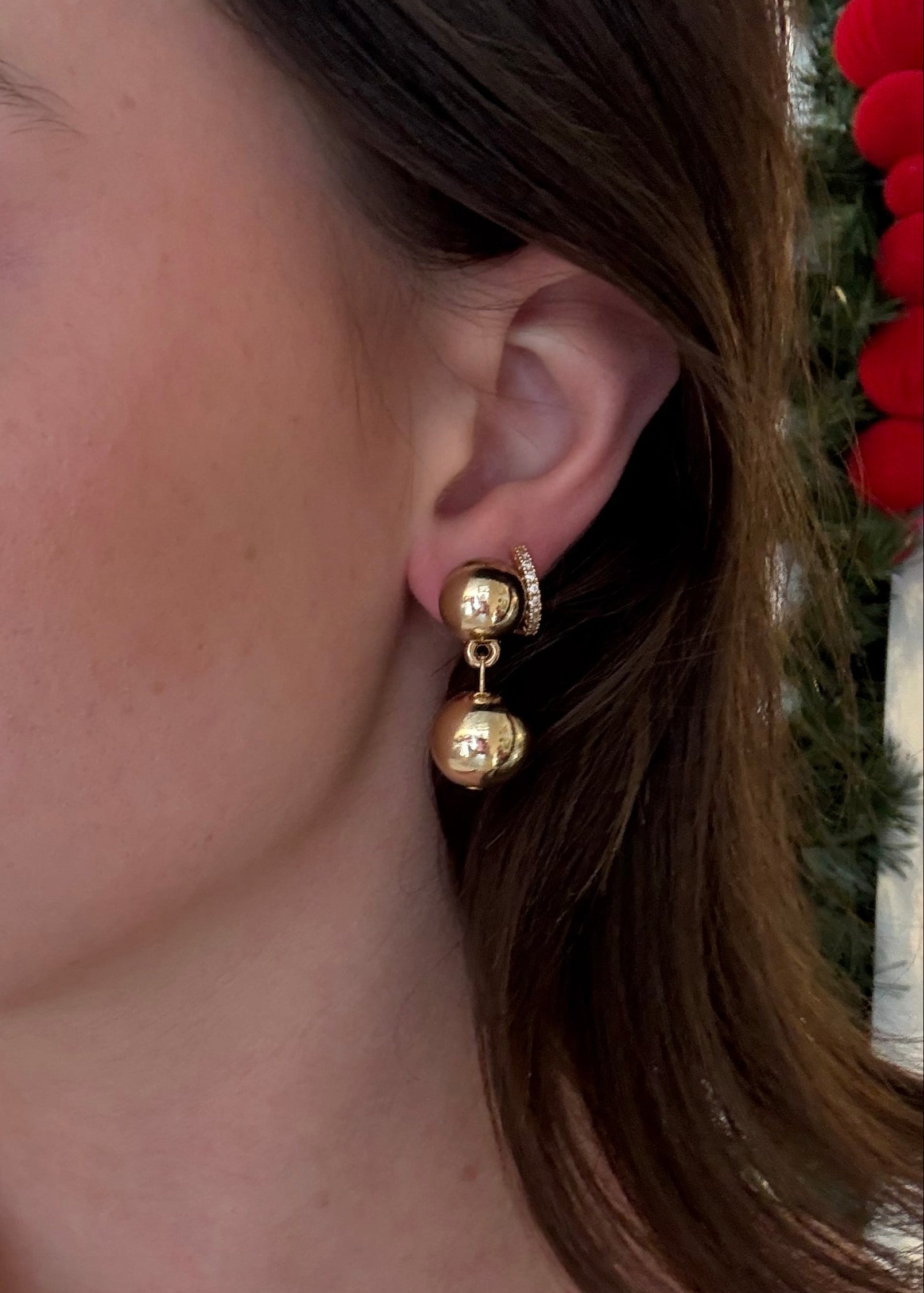 Close-up of a person wearing gold hoop earrings with a blurred background