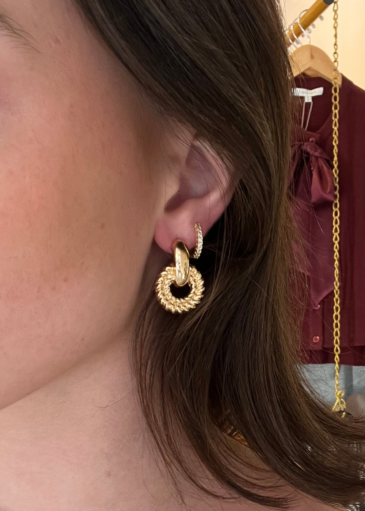 Close-up of a person wearing a gold earring with a blurred background