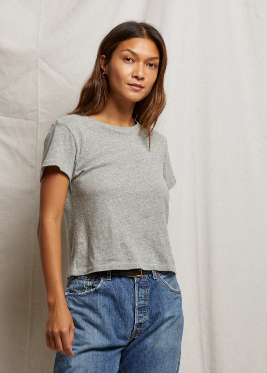 Woman wearing a gray t-shirt and blue jeans against a plain background