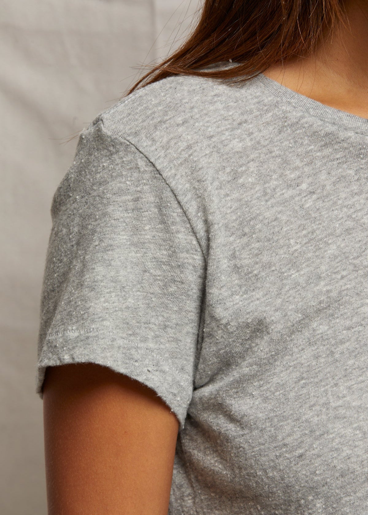 Gray t-shirt worn by a person on a neutral background