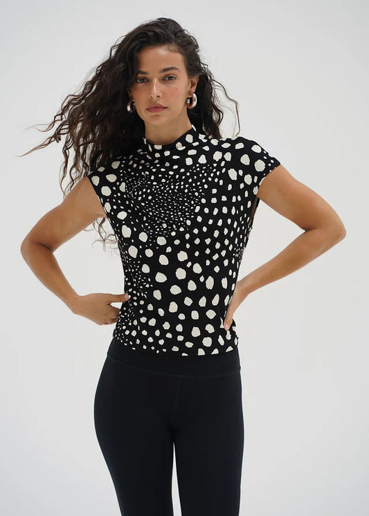 Woman wearing a black and white polka dot top and black leggings on a white background. LNA Clothing.