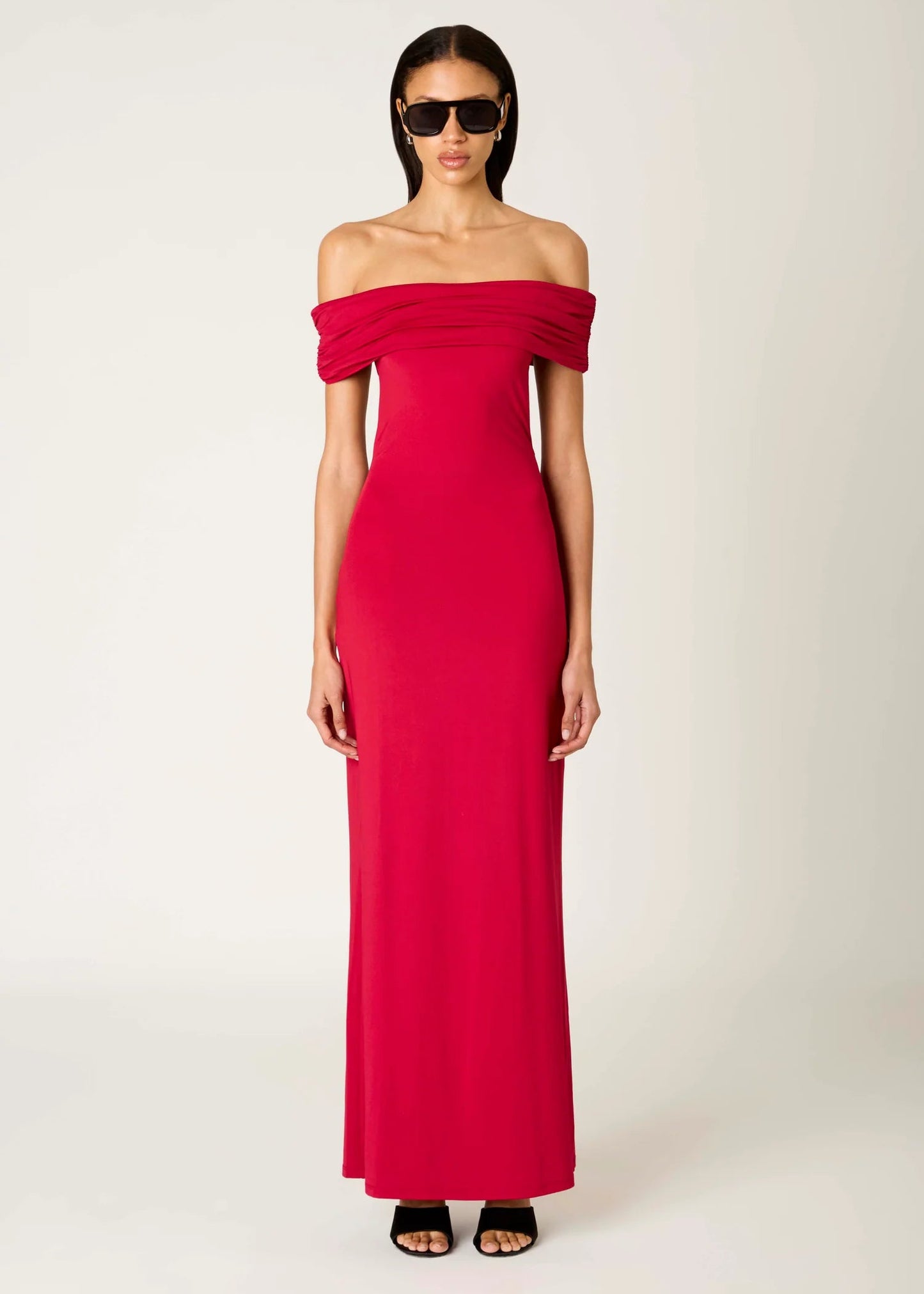 Woman wearing a red off-shoulder gown on a white background