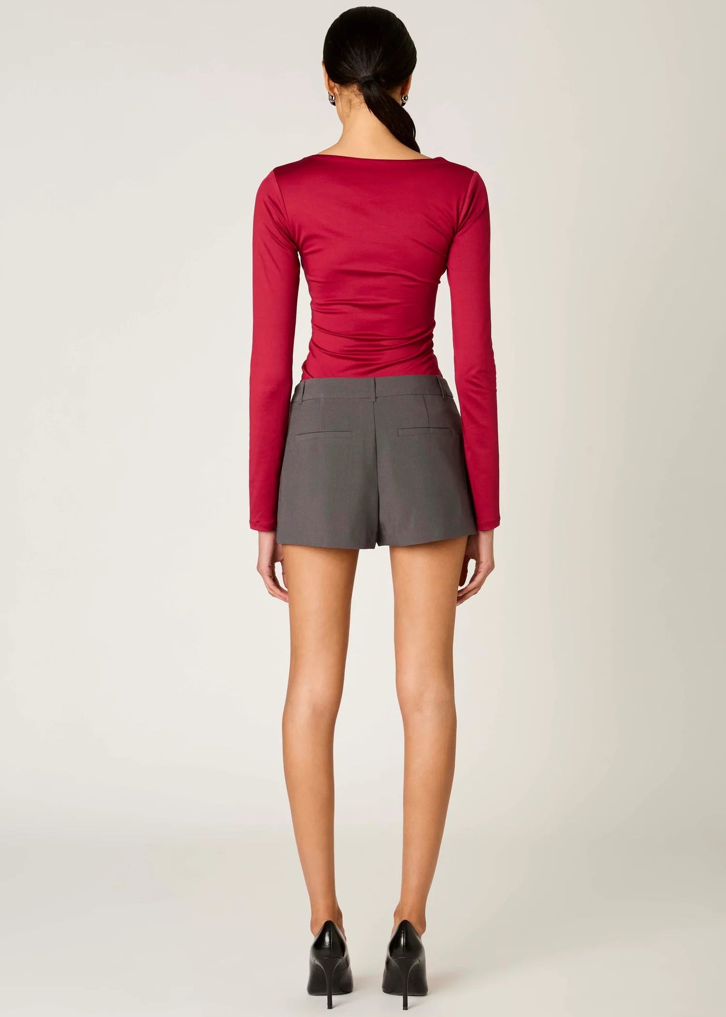 Person wearing a red long-sleeve top and gray skirt on a white background