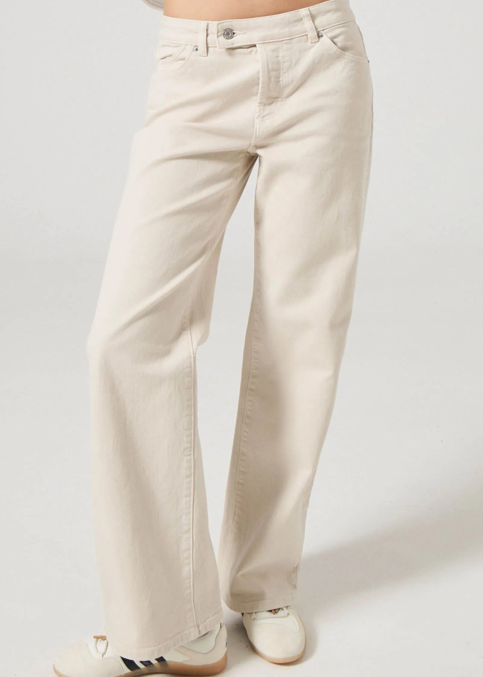 Beige pants worn by a person on a plain background. Rollas heidi low rise jeans. fayetteville arkansas.