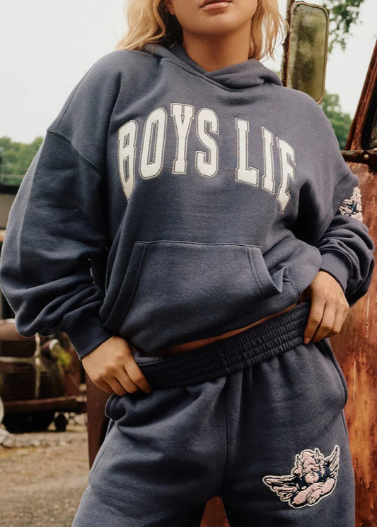 Person wearing a 'BOYS LIE' hoodie with a vintage vehicle in the background