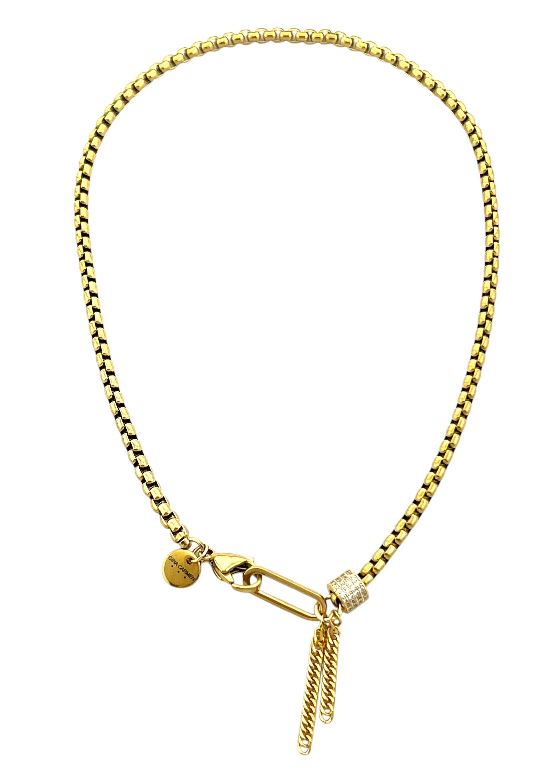 Gold bracelet with a small tag and chain on a white background