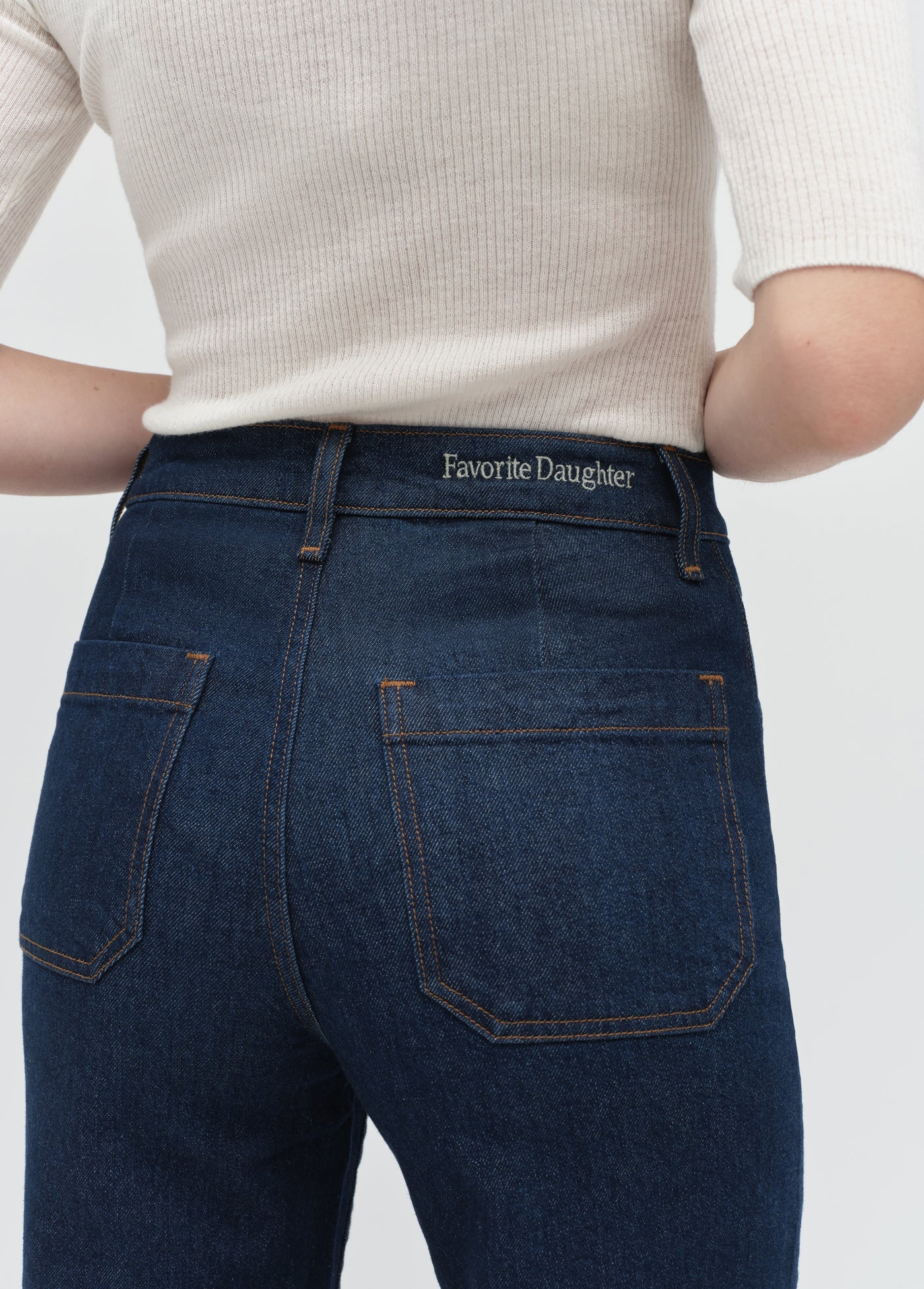 Dark blue jeans with 'Favorite Daughter' branding on a white background