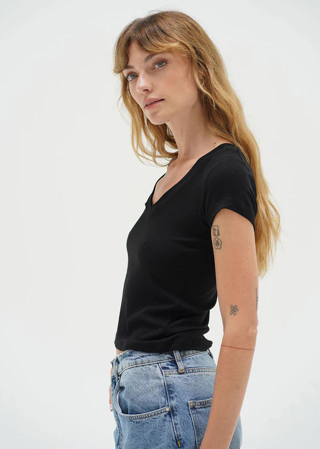 Woman wearing a black t-shirt and blue jeans against a white background