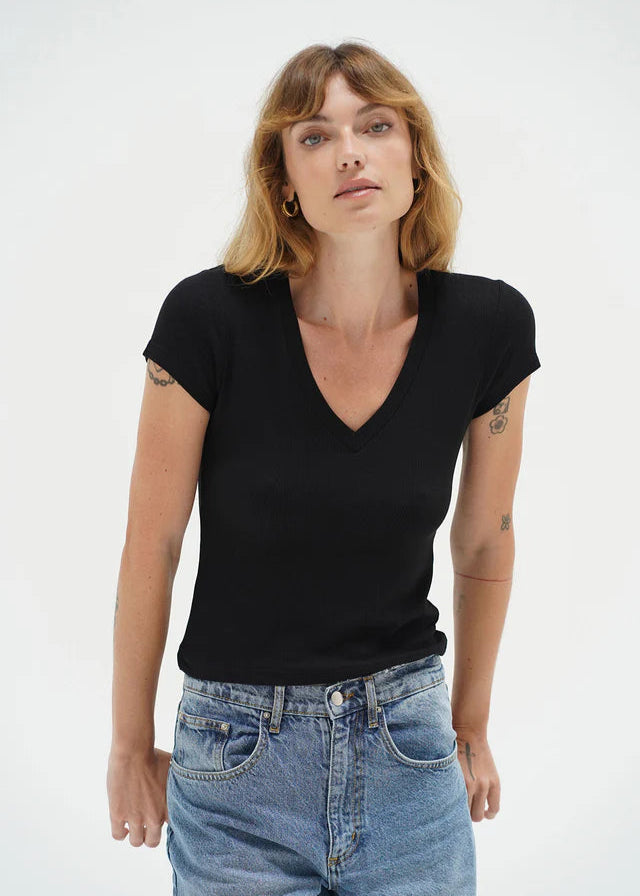 Woman wearing a black t-shirt and blue jeans against a white background. LNA Clothing.
