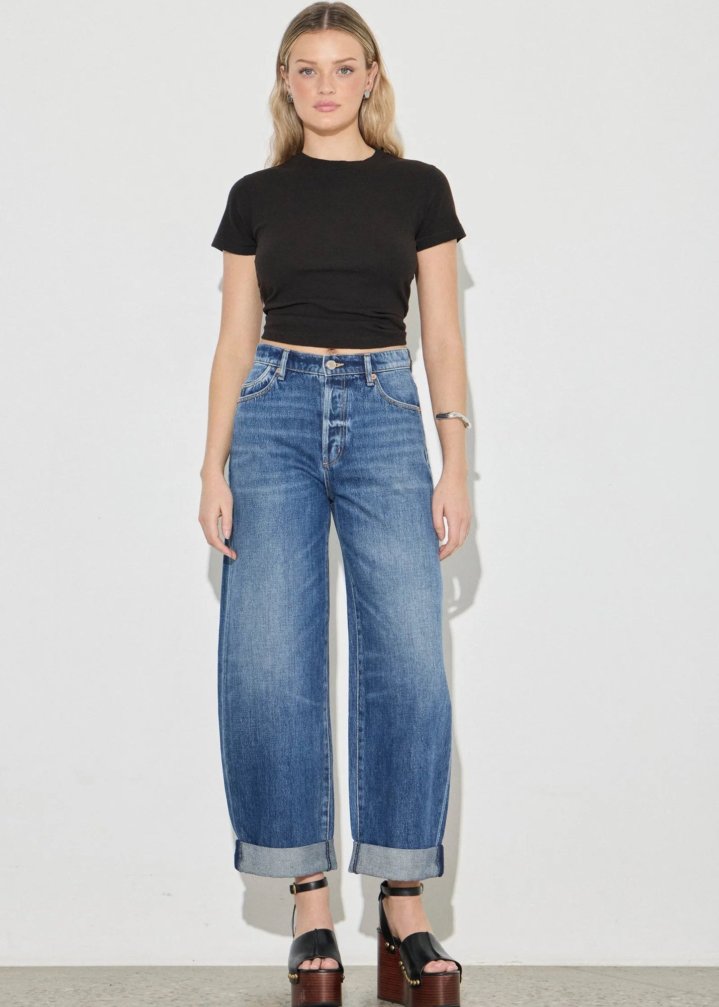 Woman wearing a black t-shirt and blue jeans against a white background