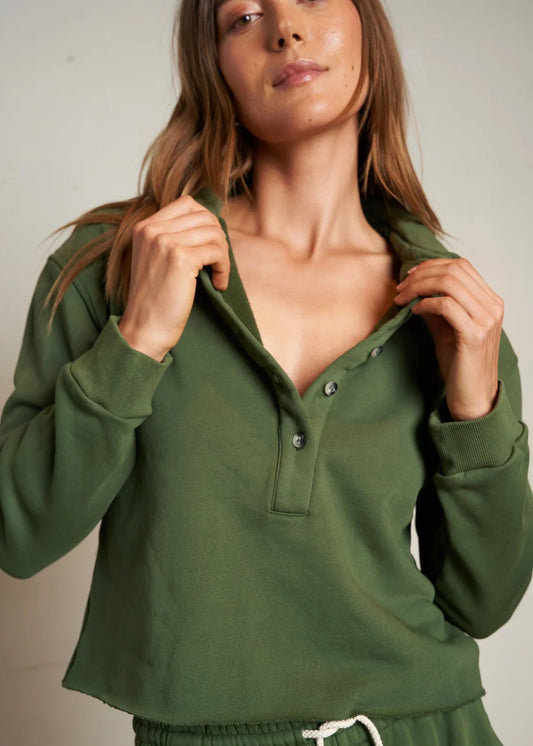 Woman wearing a green long-sleeve top with a plain background