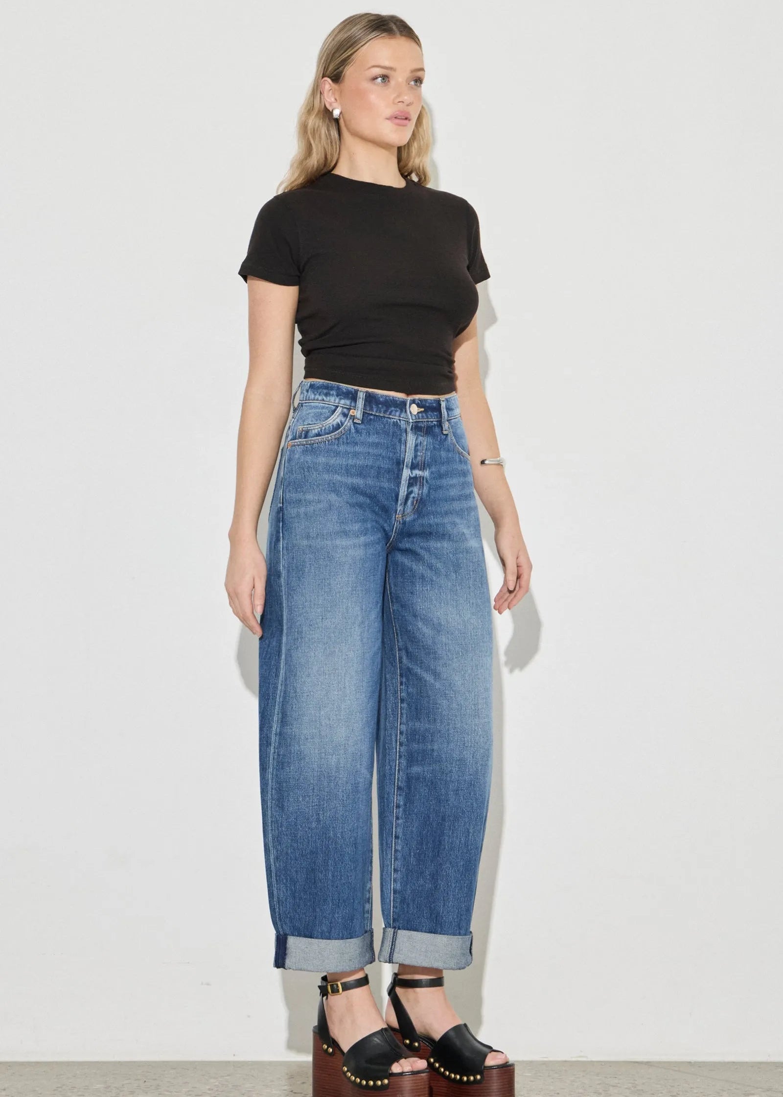 Woman wearing a black t-shirt and blue jeans against a white background