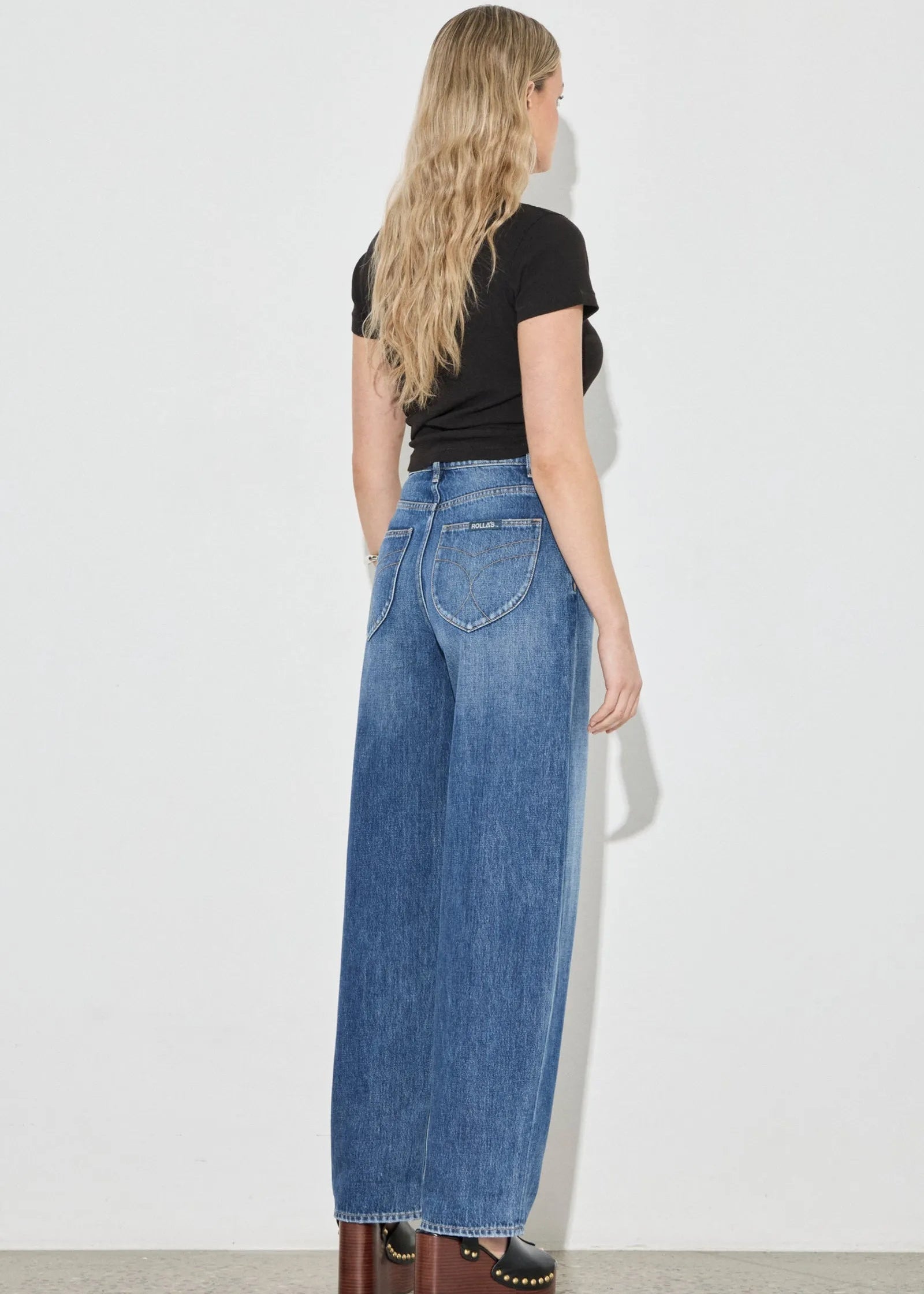 Woman wearing blue jeans and a black top on a white background