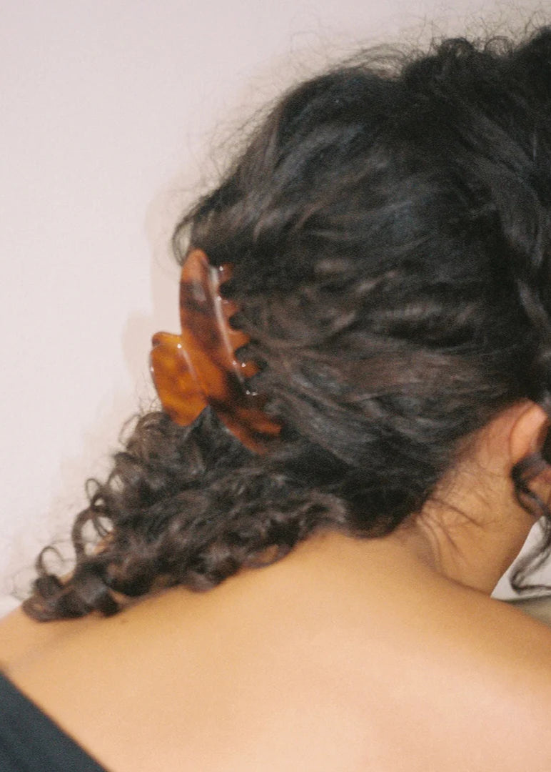 Person with styled hair using a hair clip against a plain background